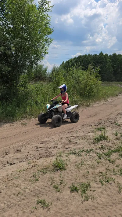 Quad na piaszczystej ścieżce, w tle las