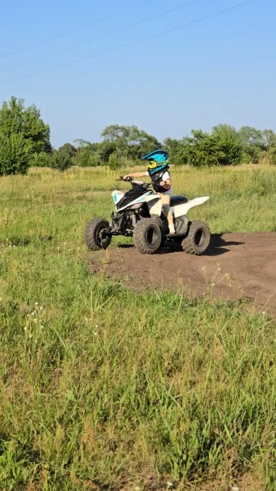 Quad na łące, jeździec w niebieskim kasku
