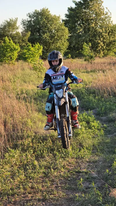 Dziecko na motocyklu crossowym na ścieżce wśród wysokich traw