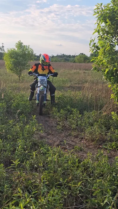 Dziecko w czerwonym kasku na motocyklu crossowym na polnej drodze