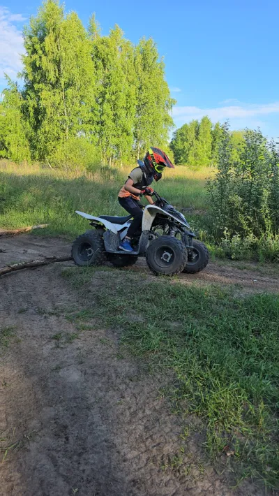Biały quad na piaszczystym podjeździe, błękitne niebo