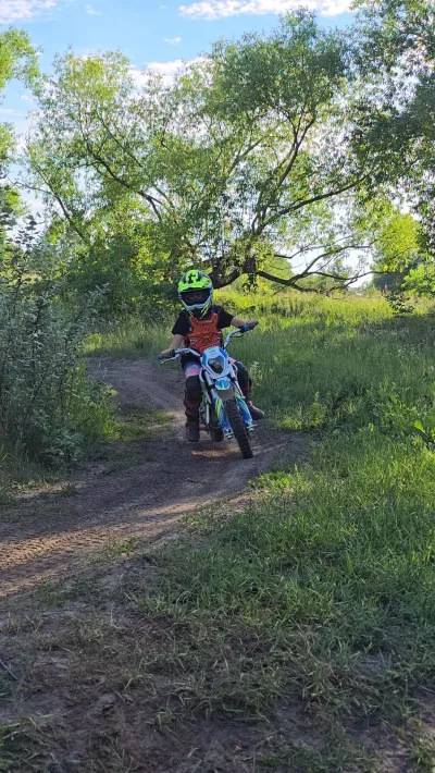 Motocykl crossowy na leśnej ścieżce pod drzewami