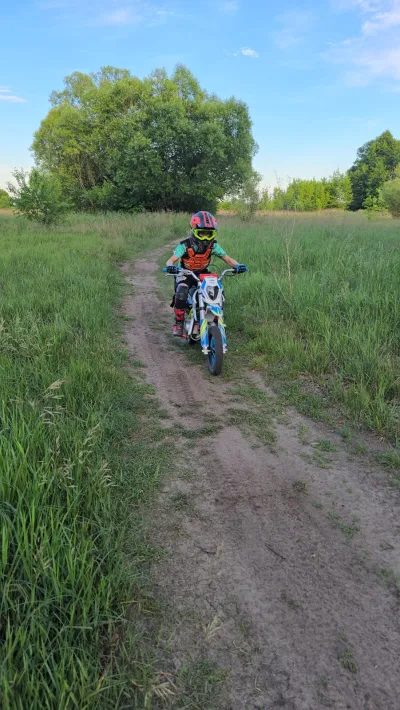 Dziecko na motocyklu crossowym na ścieżce przez łąkę