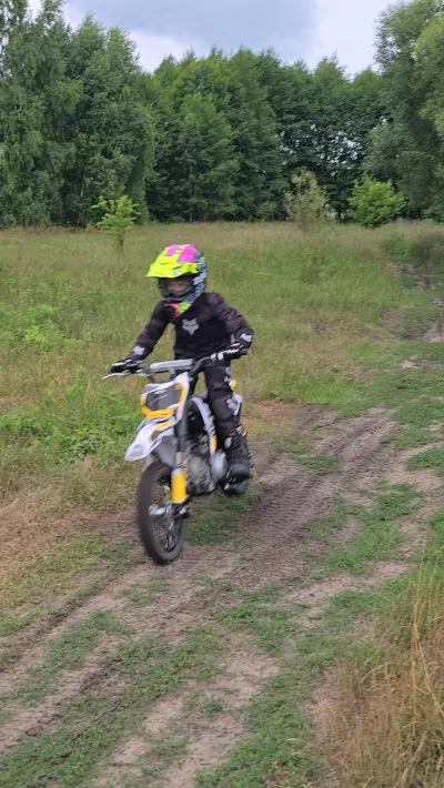 Dziecko na motocyklu crossowym w wysokiej trawie