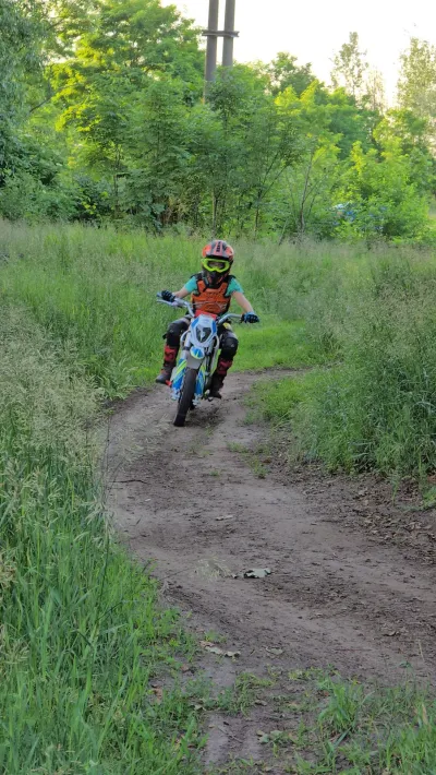 Motocykl crossowy na polnej drodze, jeździec w pomarańczowym stroju